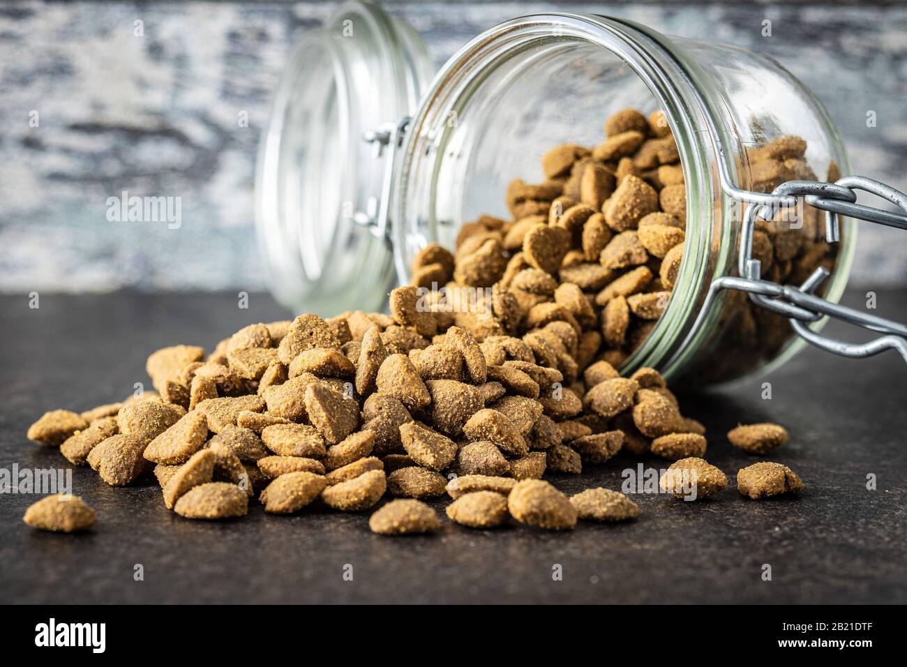 Dried kibble pet food in jar. Heart shape dried animal food on old table. Stock Photo