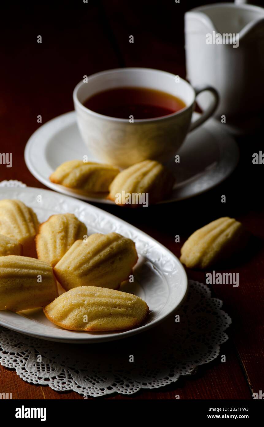Traditional French Madeleines with cup of tea on dark wooden background Stock Photo