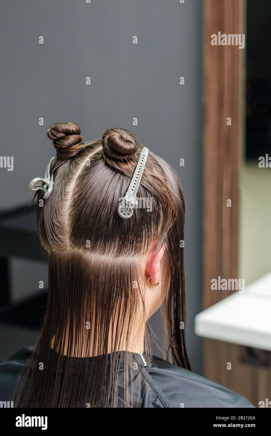 Dividing woman's hair in sections with clips during hair extension in