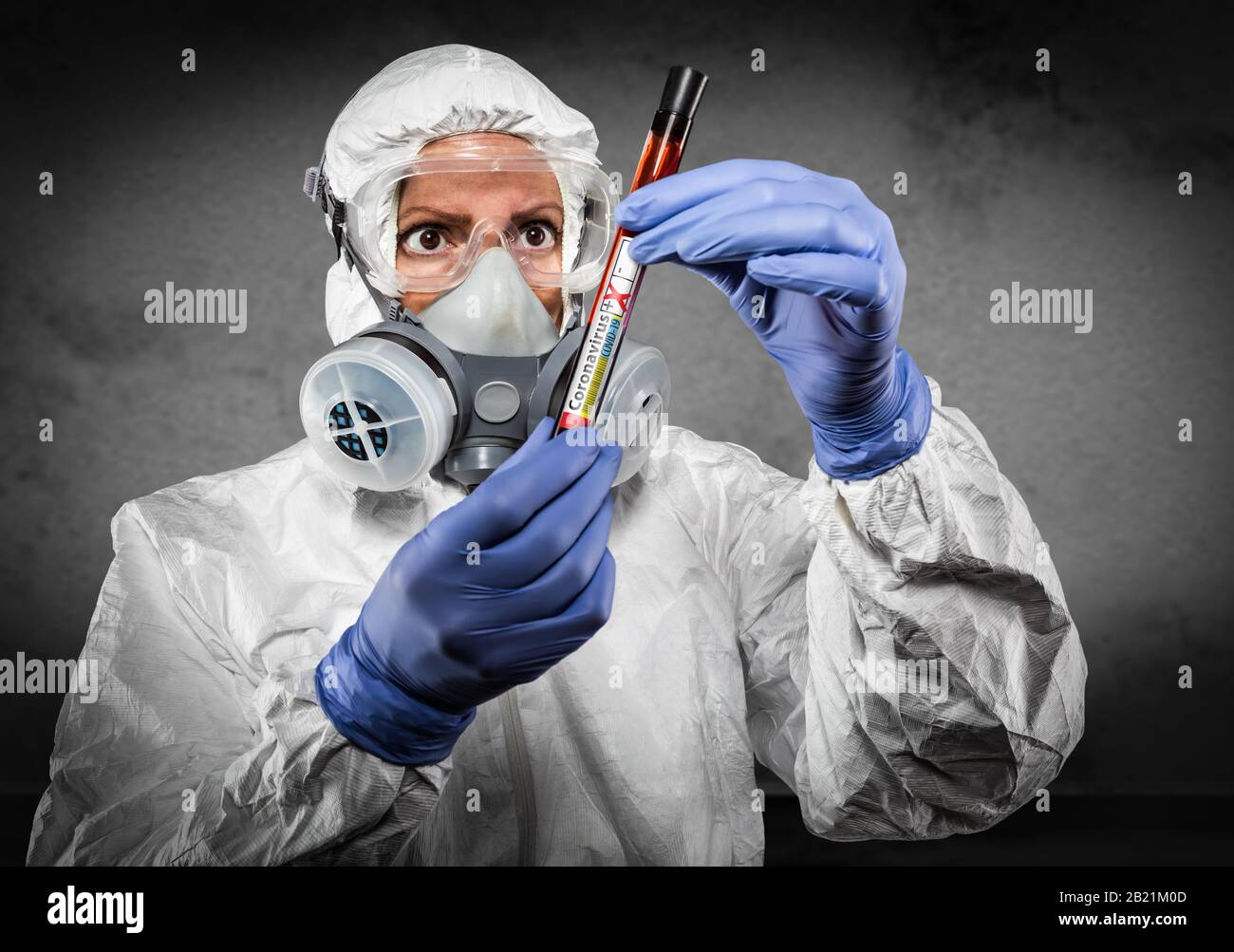 Female Doctor or Nurse In Hazmat Gear Holding Positive Coronavirus Test Tube. Stock Photo