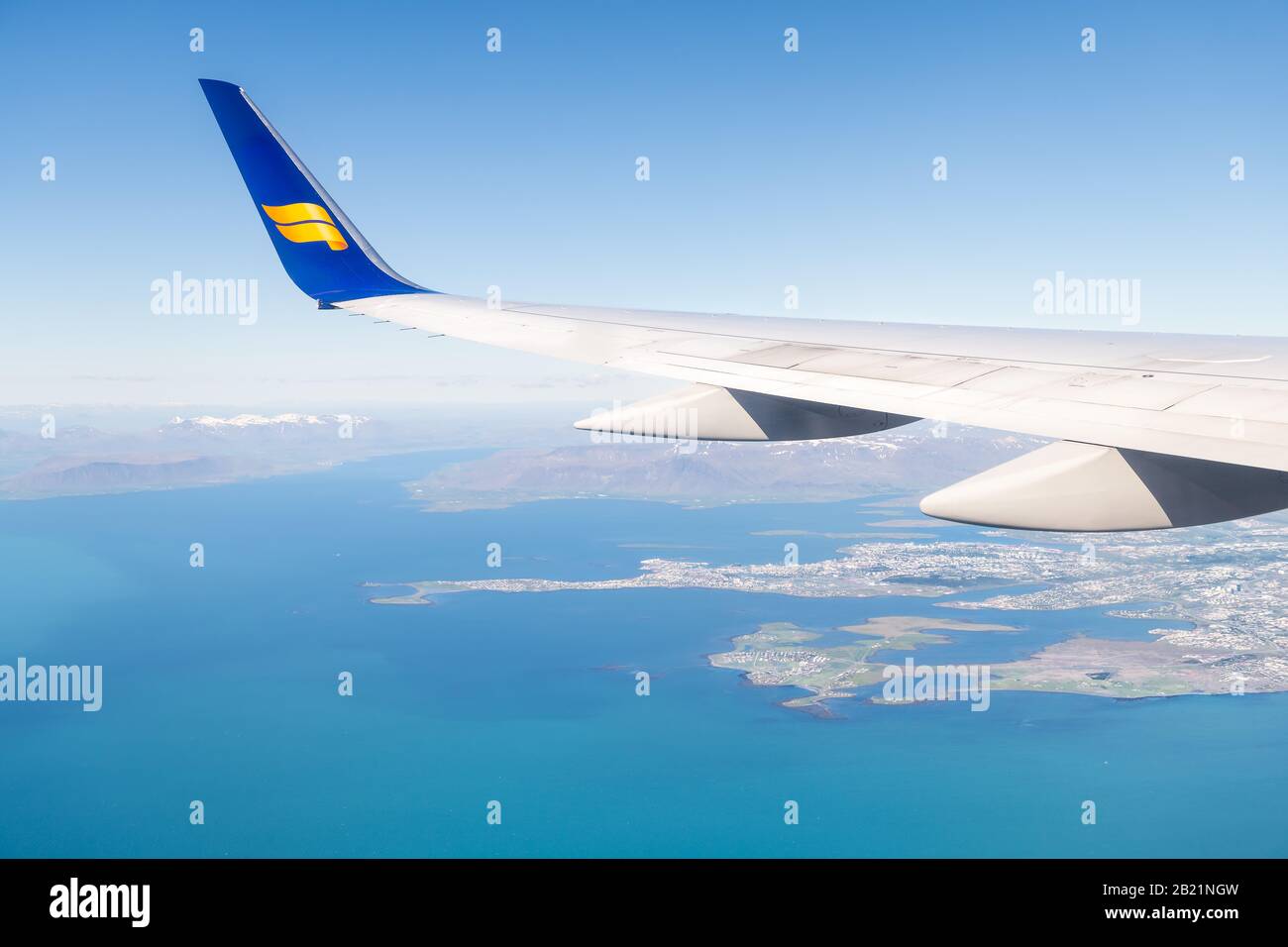 Keflavik, Iceland - June 20, 2018: Icelandair plane in blue sky with view from window high angle view over Atlantic Arctic ocean and city, mountains i Stock Photo