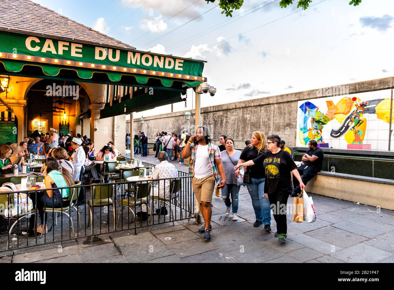 New Orleans, USA - April 22, 2018: People in line waiting to enter Cafe Du Monde restaurant sign eating beignet powdered sugar donuts and chicory coff Stock Photo