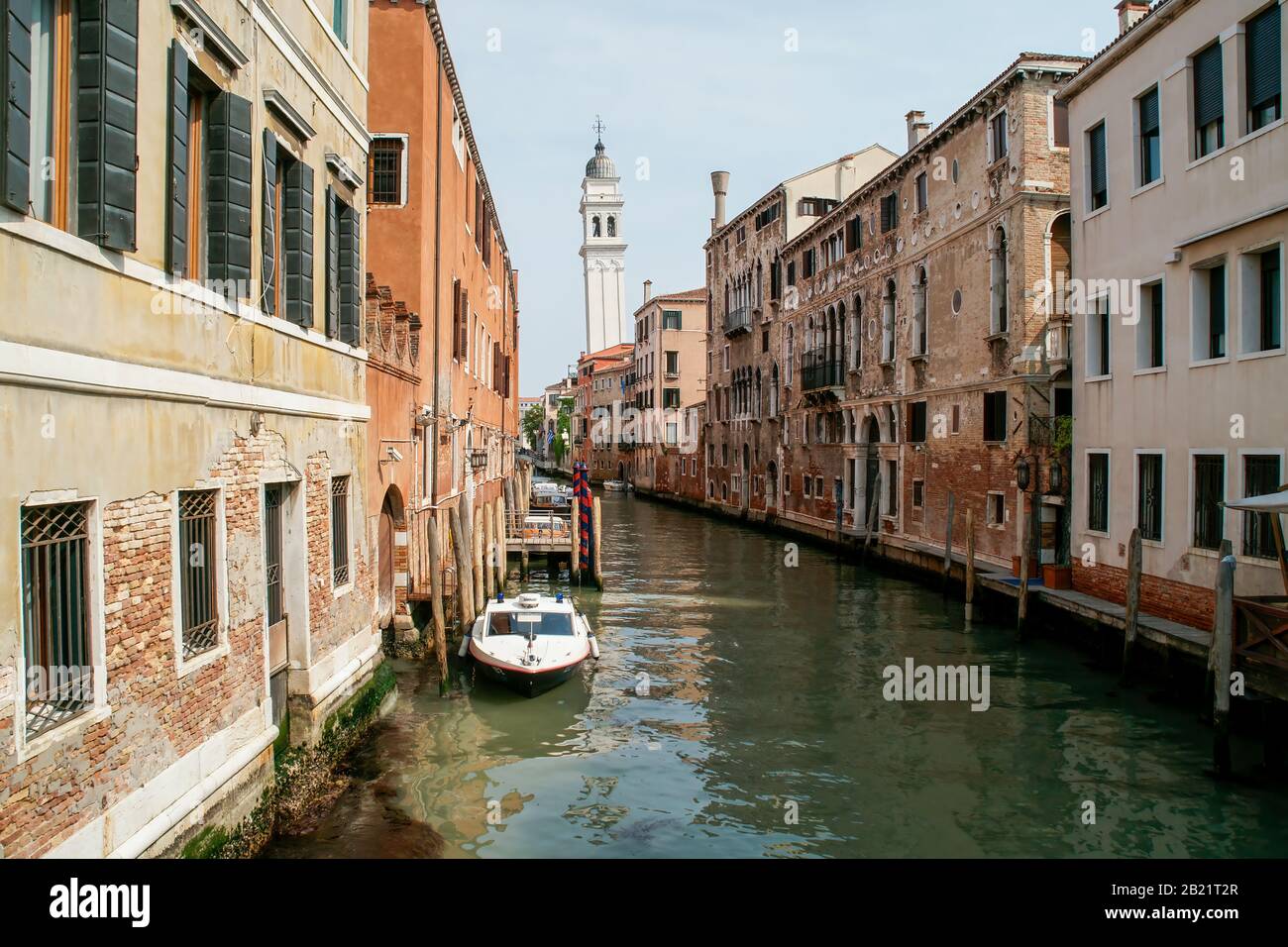 Looking down a canal lined with buildings. In the distance is the leaning bell tower of the church of San Giorgio dei Greci; Greek Orthodox Cathedral Stock Photo