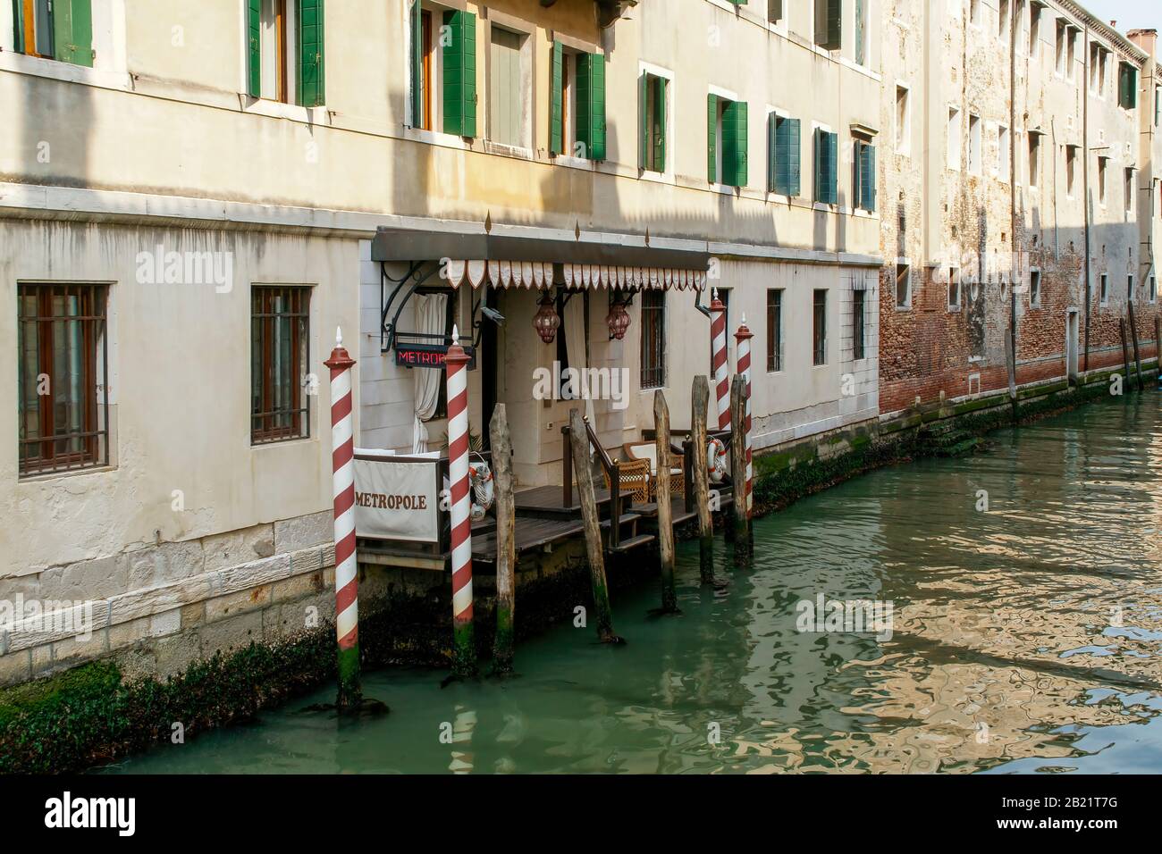 The canal or Water Taxi entrance of the Metropole Hotel. Traditional striped mooring poles. Venice, Italy. Stock Photo