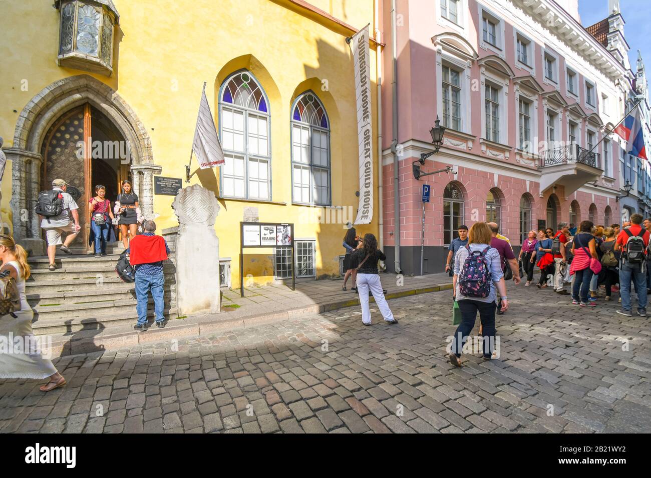 Tourists gather near a street musician performer playing violin in the Old Town center of Medieval Tallinn Estonia. Stock Photo