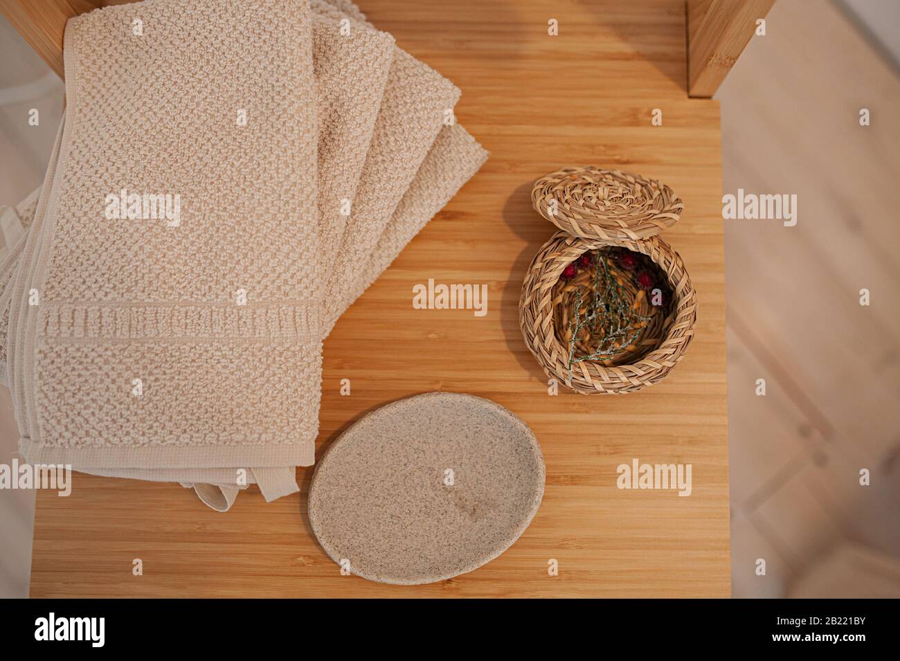natural eco-friendly bath accessories, cotton towels, stone soap dish and wicker basket, on a wooden tabletop Stock Photo