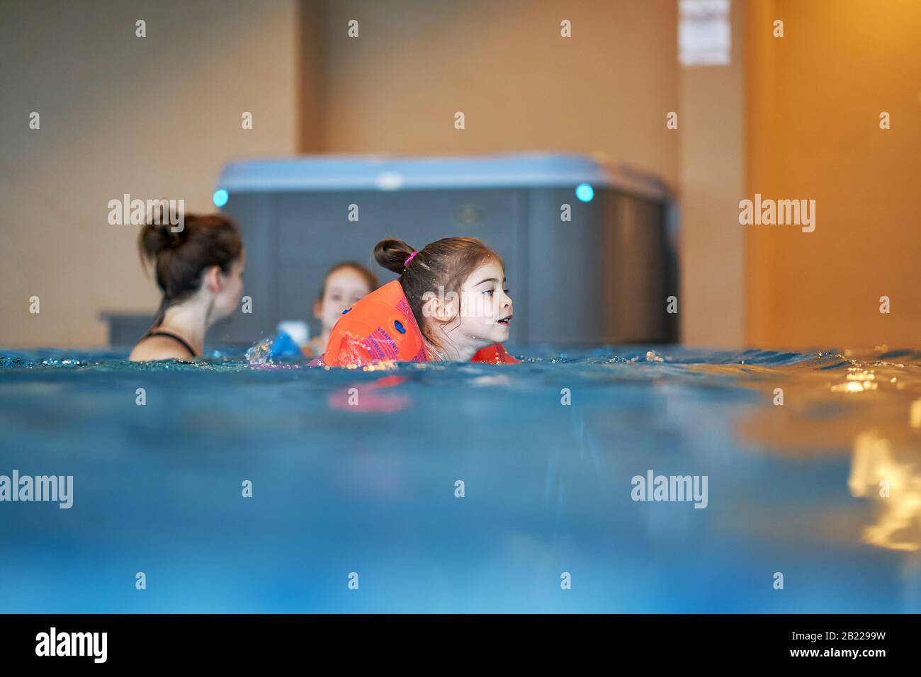 Adorable little girls play and swim in pool during the holidays Stock Photo