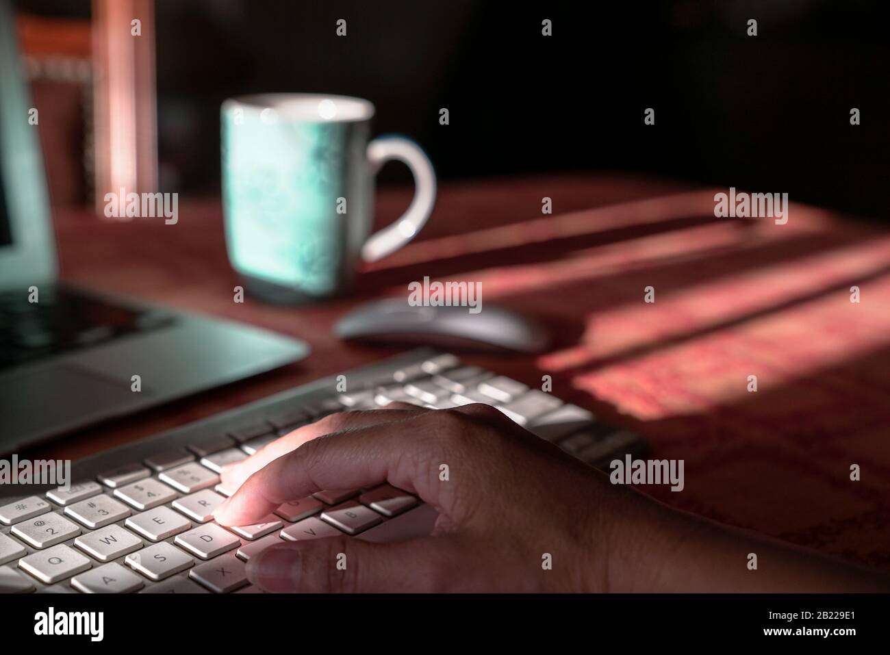 Laptop with hand on wireless keyboard. Work from home or technology concept. Stock Photo