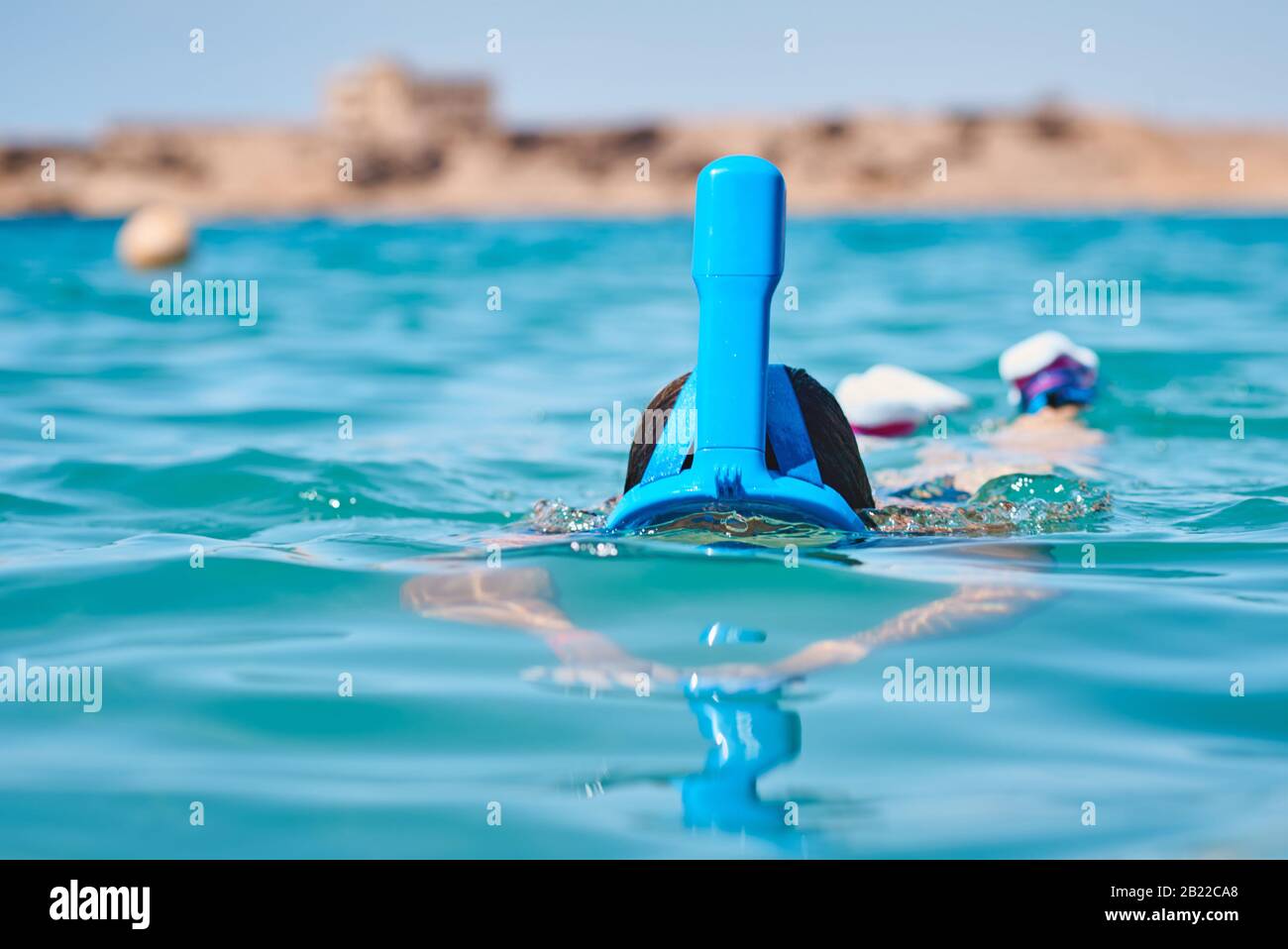 Woman with snorkel full face mask diving in blue sea summer vacation