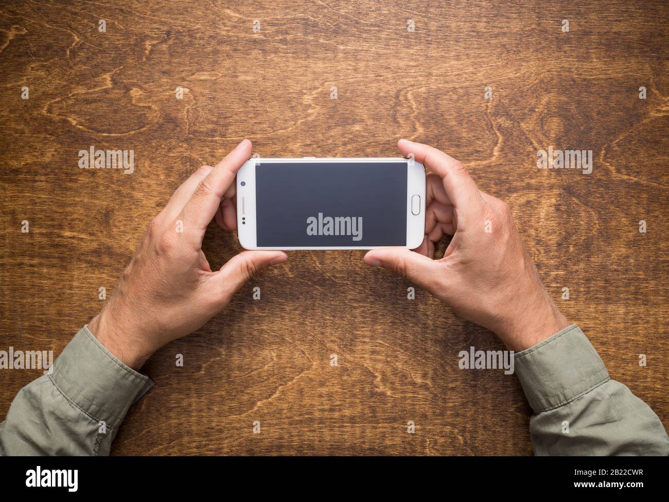 Man's hands on the table holding smart phone. Stock Photo