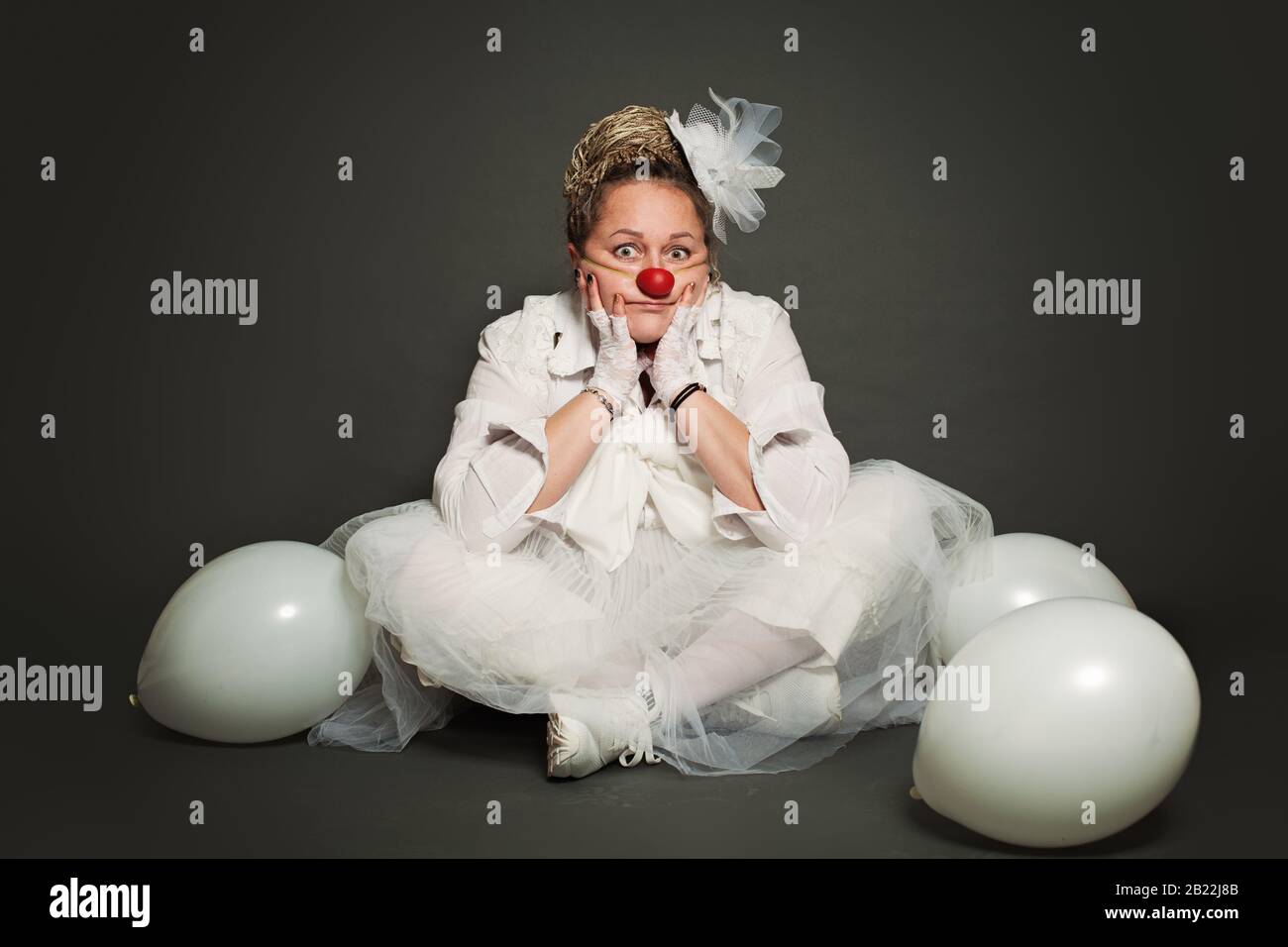 Woman clown on gray background, studio portrait. Performance Actress, White Clown Character Stock Photo