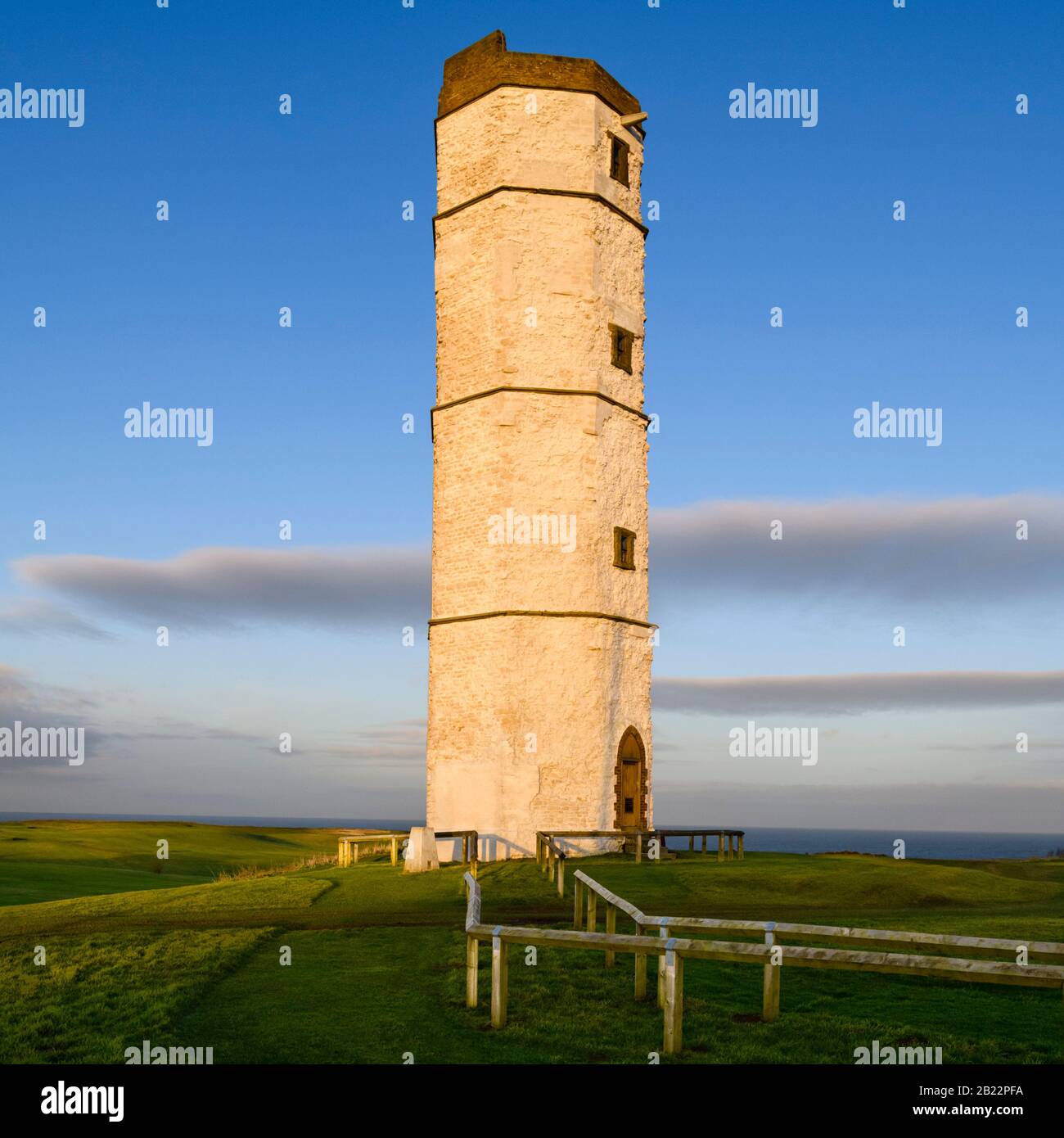 Exterior of old sunlit Flamborough Head Lighthouse (historic tall white chalk octagonal beacon tower) & deep blue sky - near Bridlington, England, UK. Stock Photo