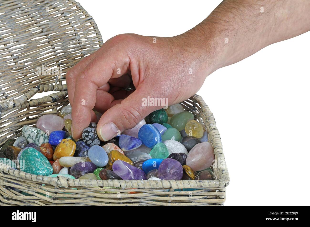 Choosing crystals to help your heal - male hand reaching into wicker basket choosing a healing crystal isolated on a white background with copy space Stock Photo