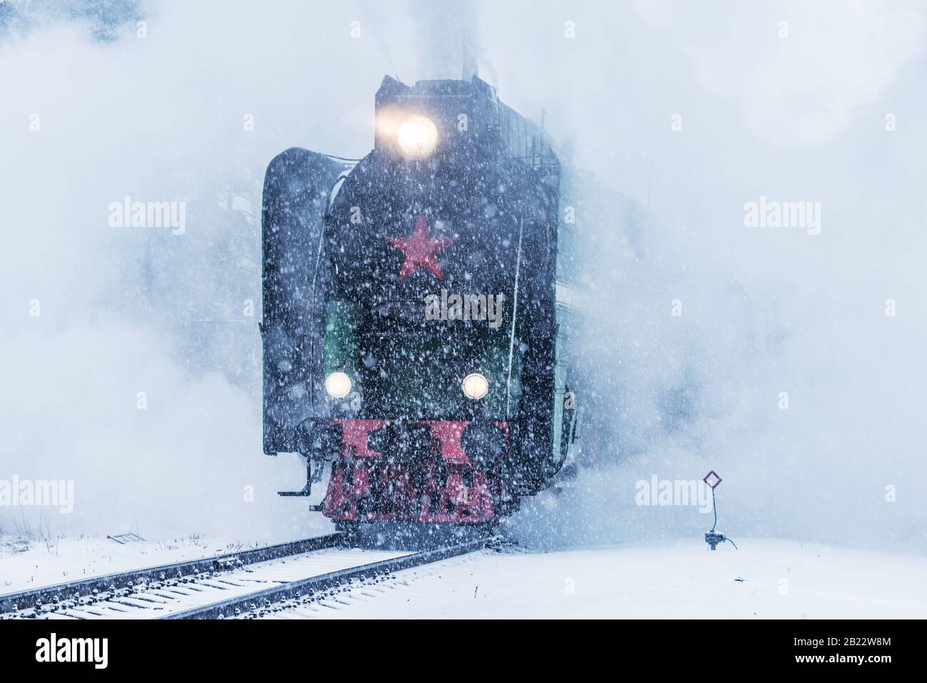Retro steam train departs from the railway station at winter snowy time ...