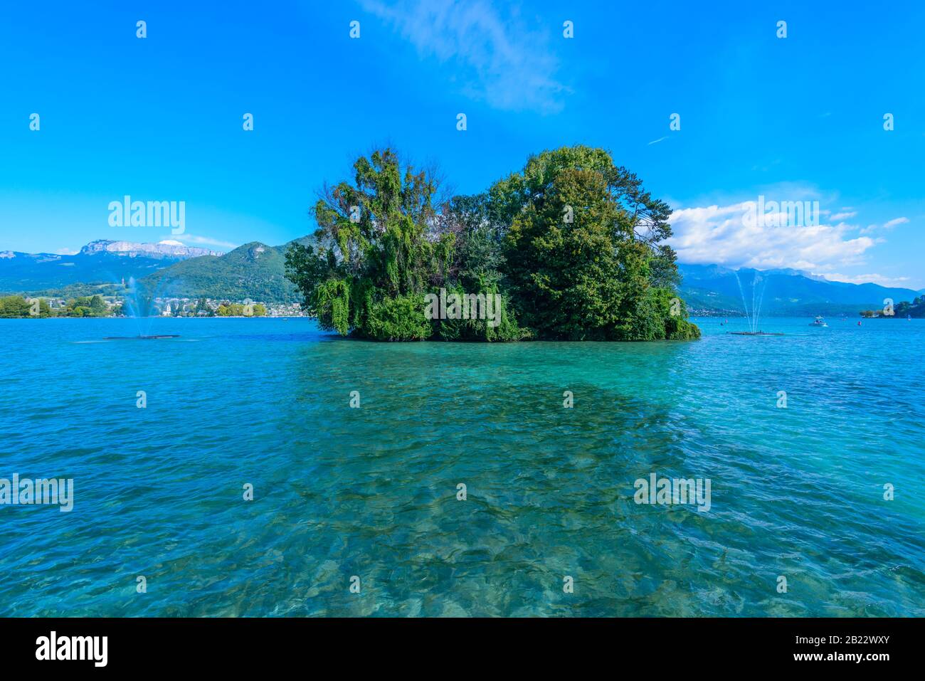 A small green island - Island of Swans (L'île des Cygnes) on Lake Annecy, one of the largest lakes in France known as the cleanest lake in Europe. Stock Photo