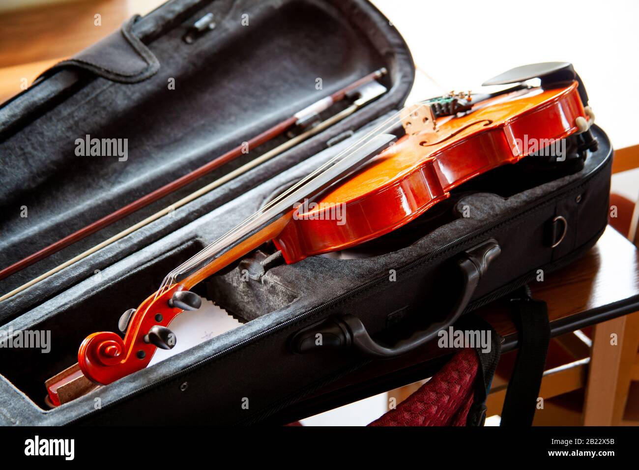 Violin with a bow laying in an open black fiddle case on the table. Classical musical string instruments group concept, nobody. Safe instrument Stock Photo
