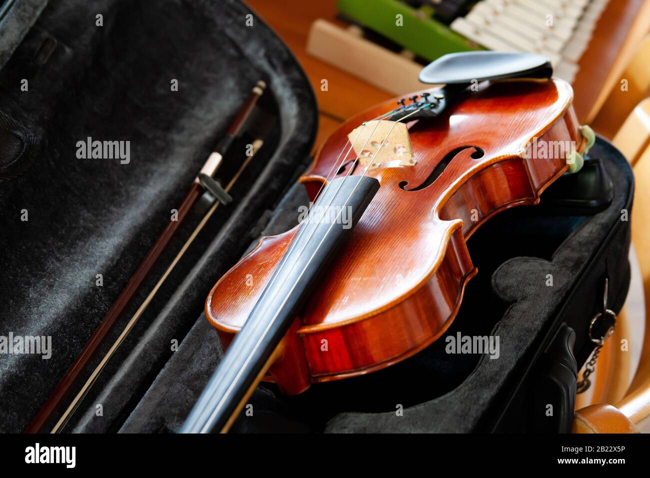 Violin fiddle with a bow laying in an open black case on the