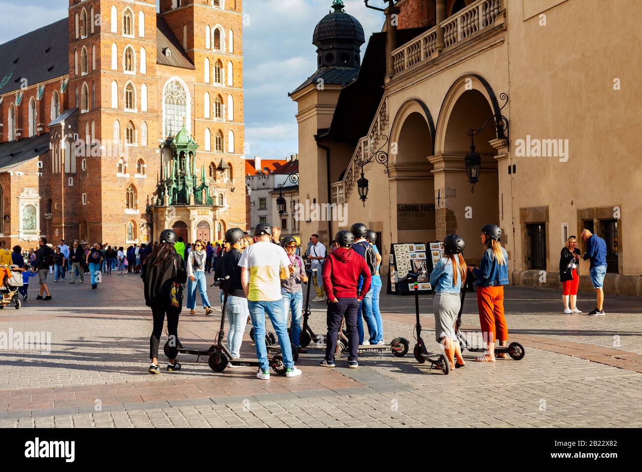Cracow, Małopolska / Poland - circa December 2019: A group of people on electric scooters standing on the market square in front of St. Mary Basilica. Stock Photo