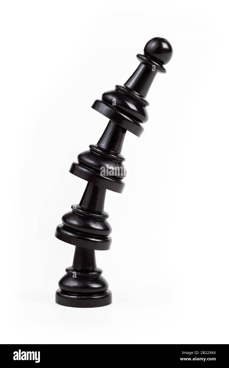 Simple leaning tower made of chess pawn pieces, curved bent construct of black game pieces standing on each other. Teamwork, cooperation, achieving Stock Photo