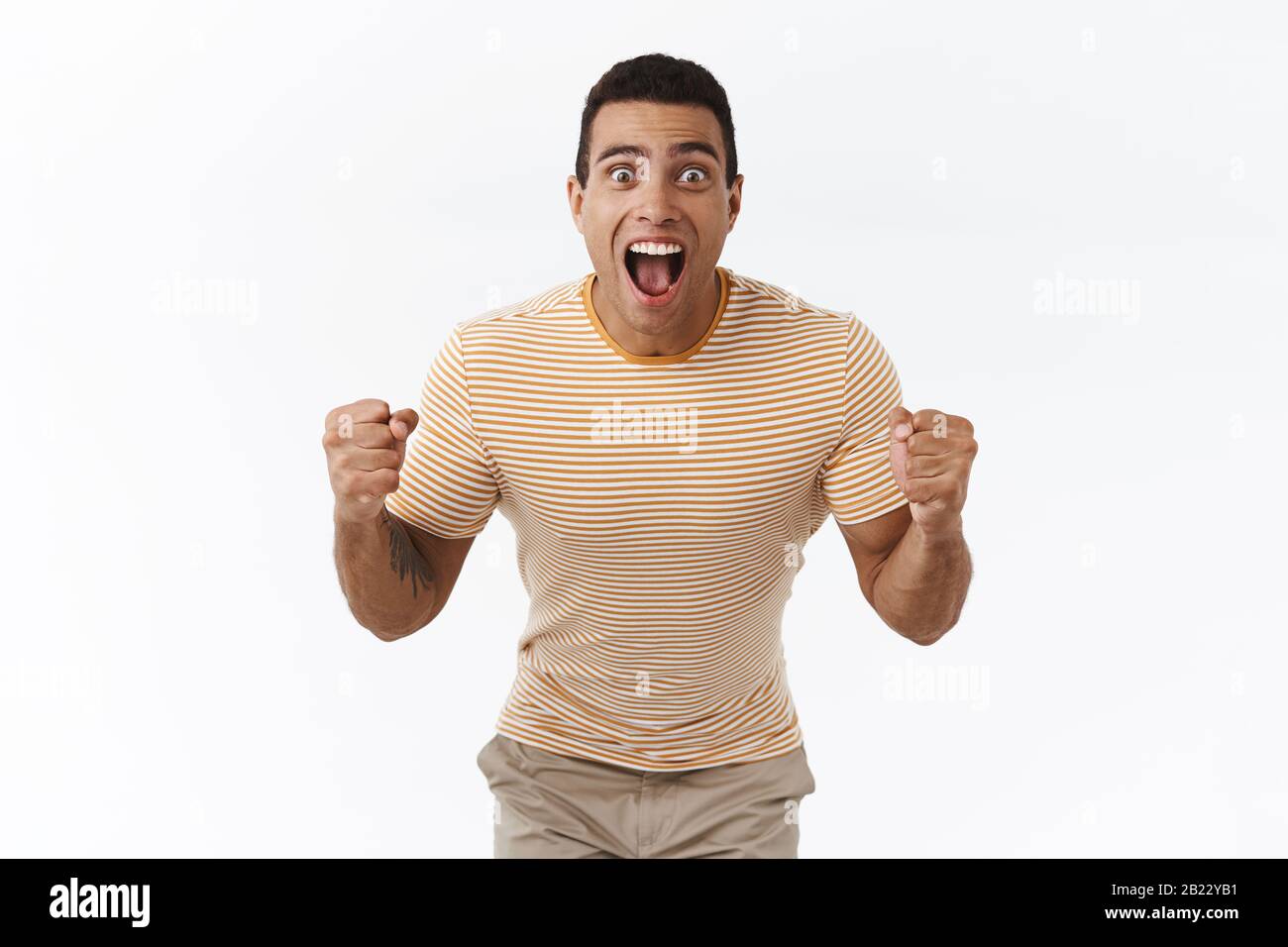 Pumped, excited handsome masculine guy winning big money, looking at score or sport match with happy, relieved expression, accomplish goal, fist pump Stock Photo