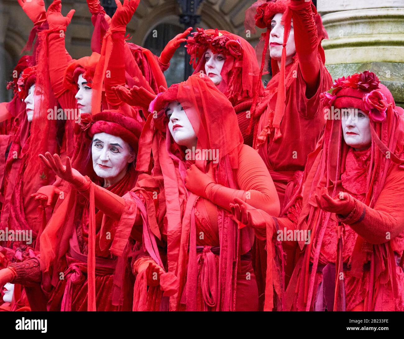 The Red Brigade of Extinction Rebellion displaying their striking poses in peaceful protest supporting action on climate change - Bristol UK Stock Photo