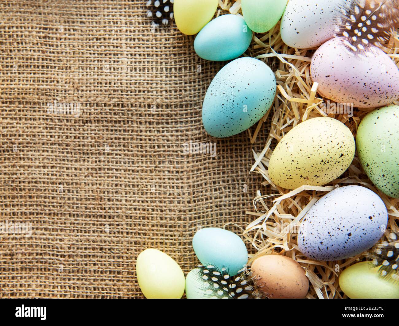 Easter eggs on a sackcloth and straw . Happy Easter  multicolored  easter eggs. Background with easter eggs. Flat lay, top view. Stock Photo