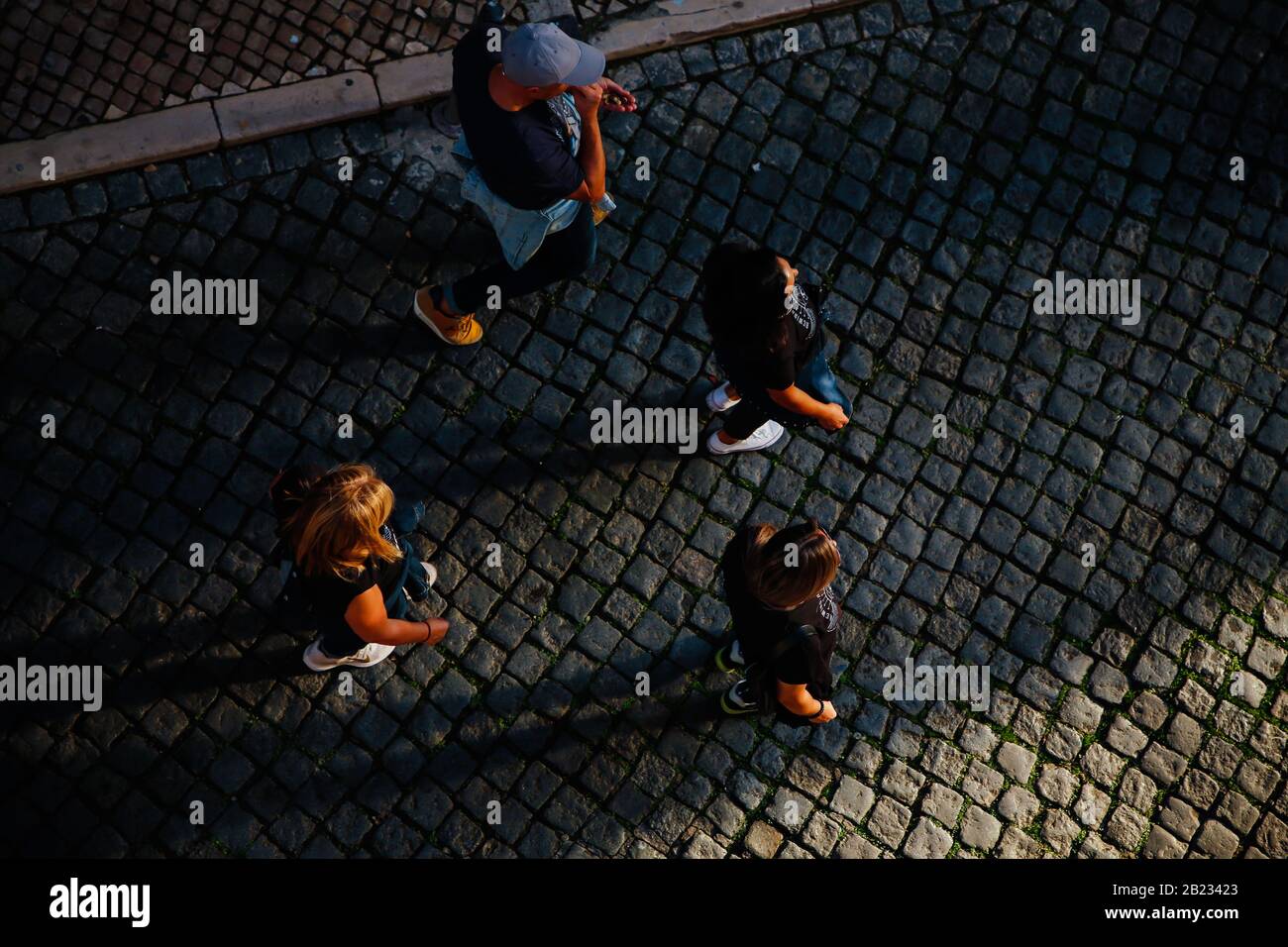 4 walkers seen from overhead on cobbled street and long morning shadows Stock Photo