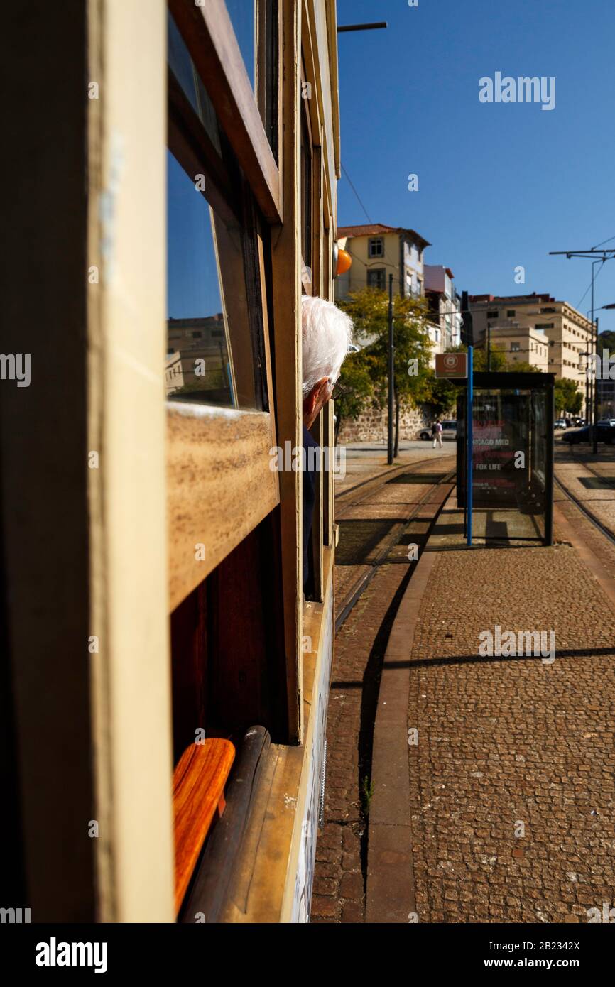Single white-haired tourist leaning out a vintage trolley window looking at sights, Lisbon, Portugal, October 9, 2019 Stock Photo