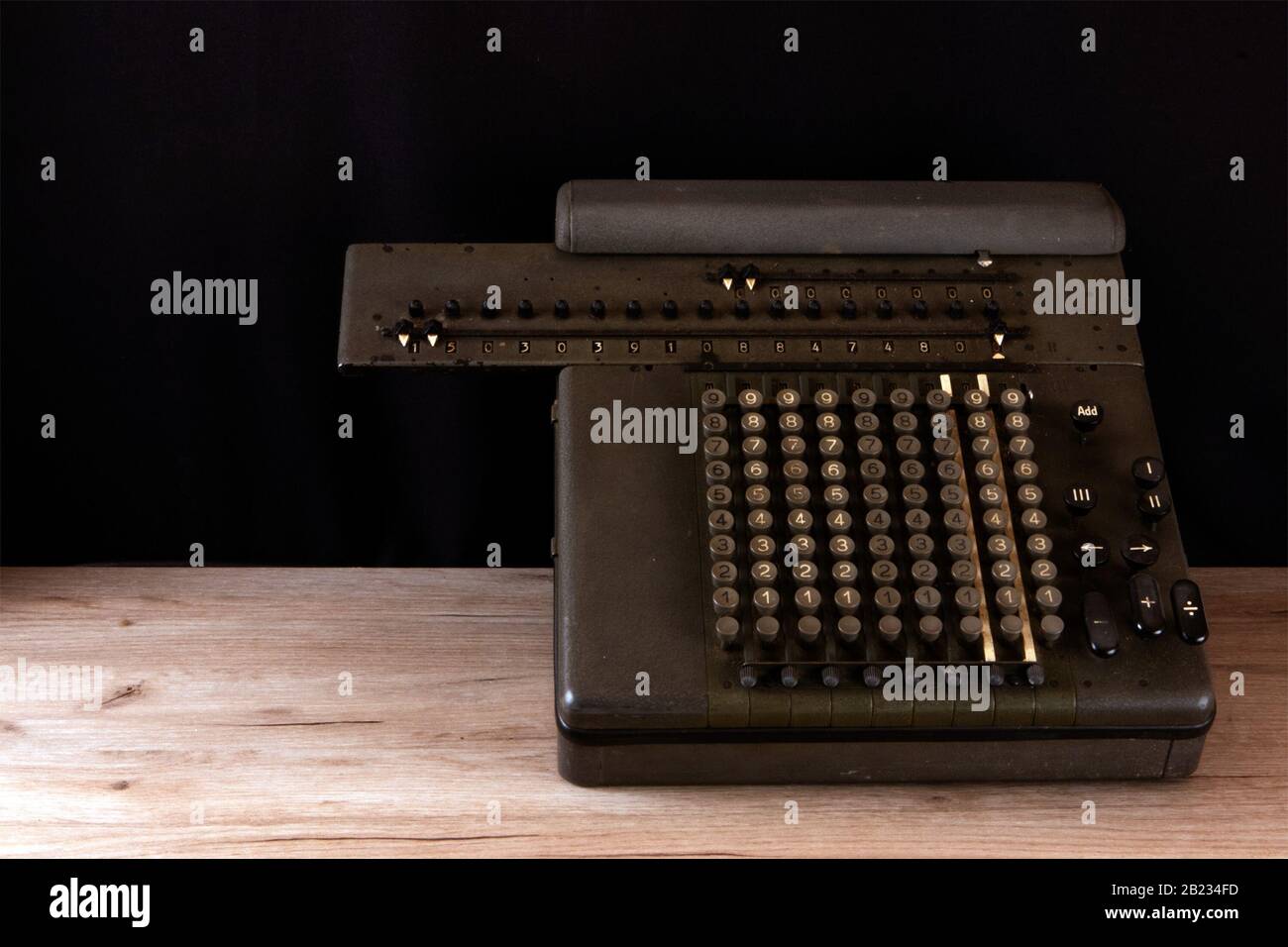 https://c8.alamy.com/comp/2B234FD/old-counting-mechanism-dusty-vintage-arithmometer-standing-on-a-wooden-board-against-black-fabric-2B234FD.jpg