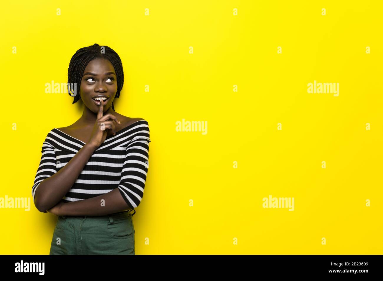 Portrait of a pretty young african woman standing isolated over yellow ...