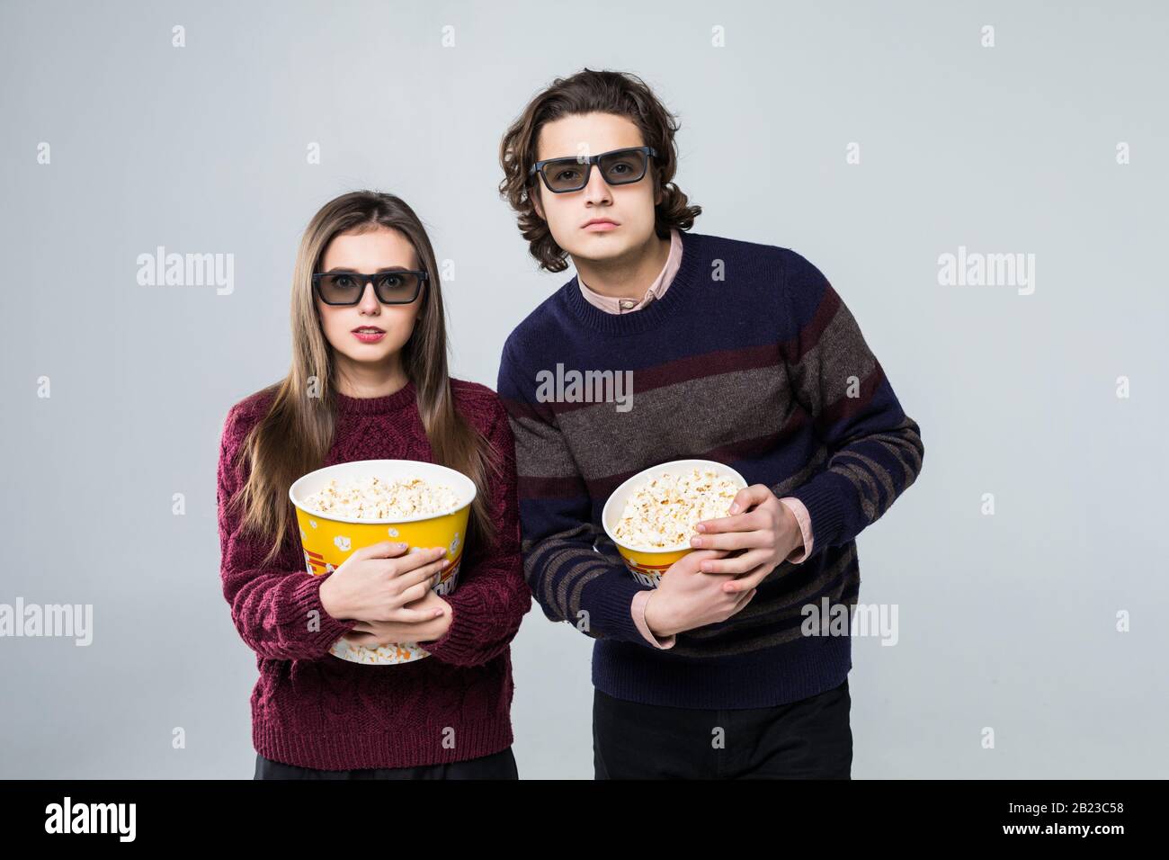 Young man and woman wearing 3D glasses and eating popcorn on white background Stock Photo