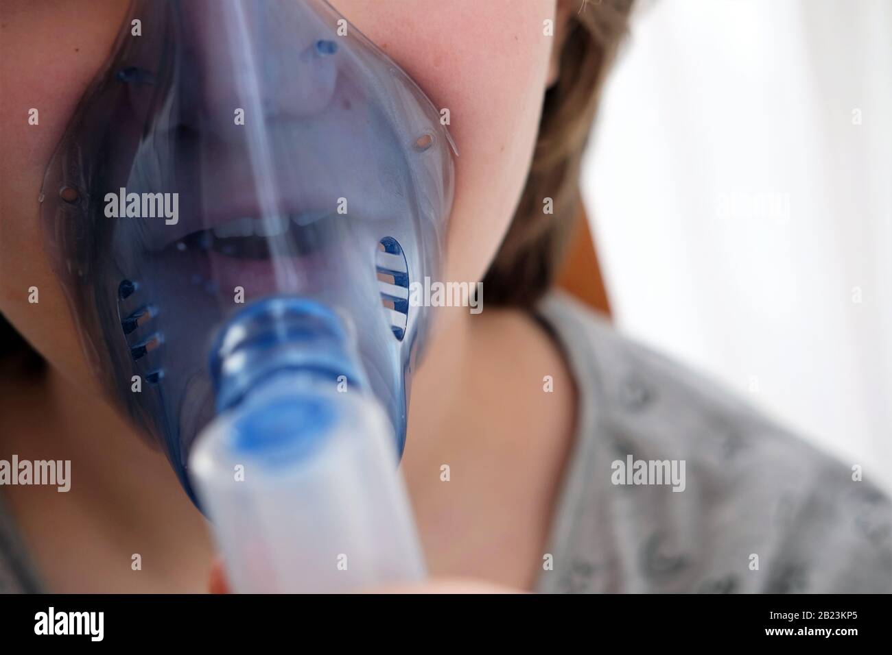 girl suffering from cough using a nebulizer to cure her condition Stock Photo