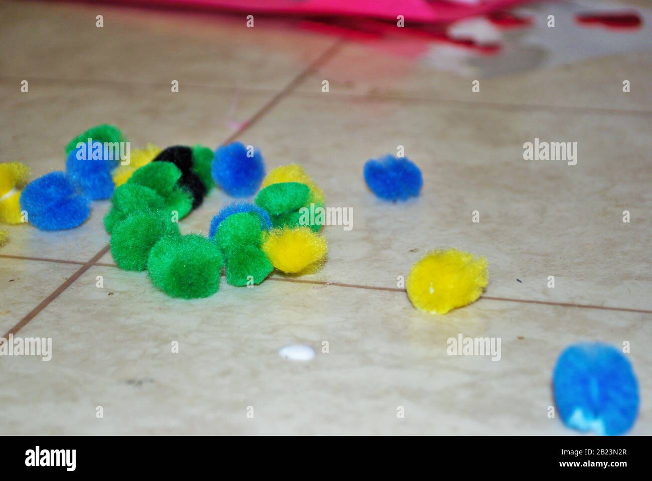 Multi colored cotton balls and glue on a linoleum floor during arts and