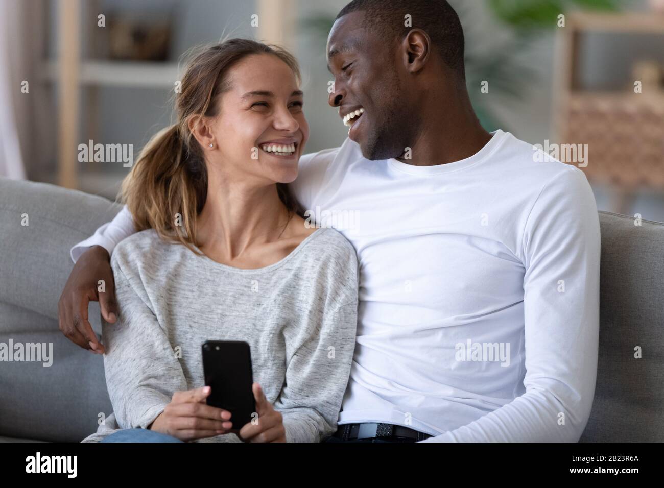 Happy African American couple having fun with phone at home Stock Photo ...