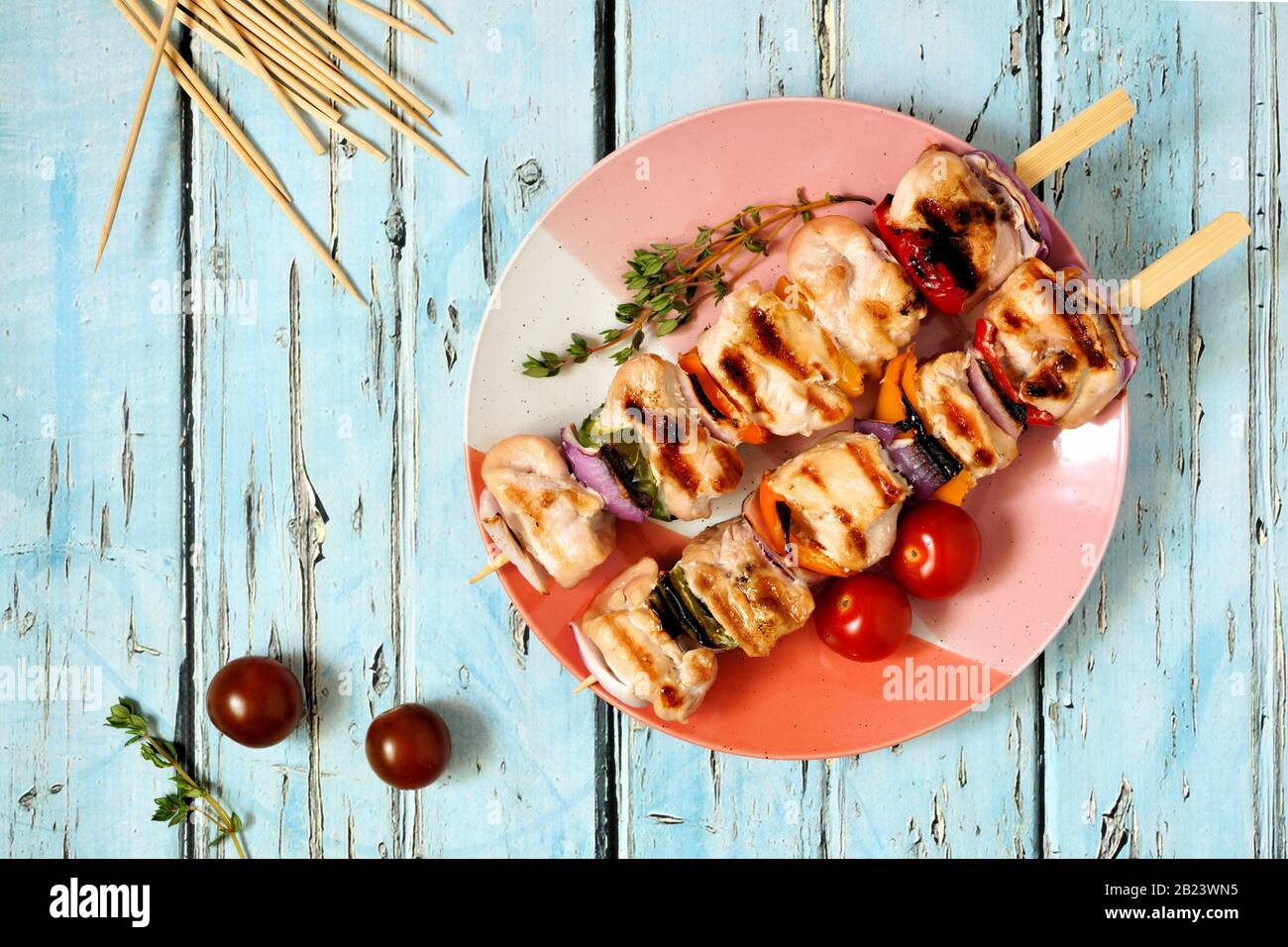Grilled chicken and vegetable kabobs on plate. Top view over a blue wood background. Summer food concept. Stock Photo