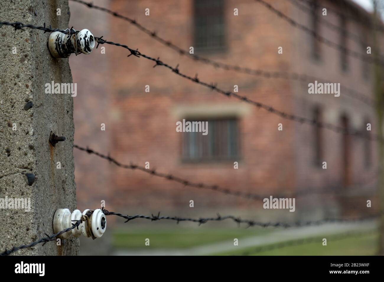 Closeup of electrified fence enclosing the buildings at Auschwitz - Birkenau Museum and Memorial of the Nazi Death Camps of World War II Stock Photo