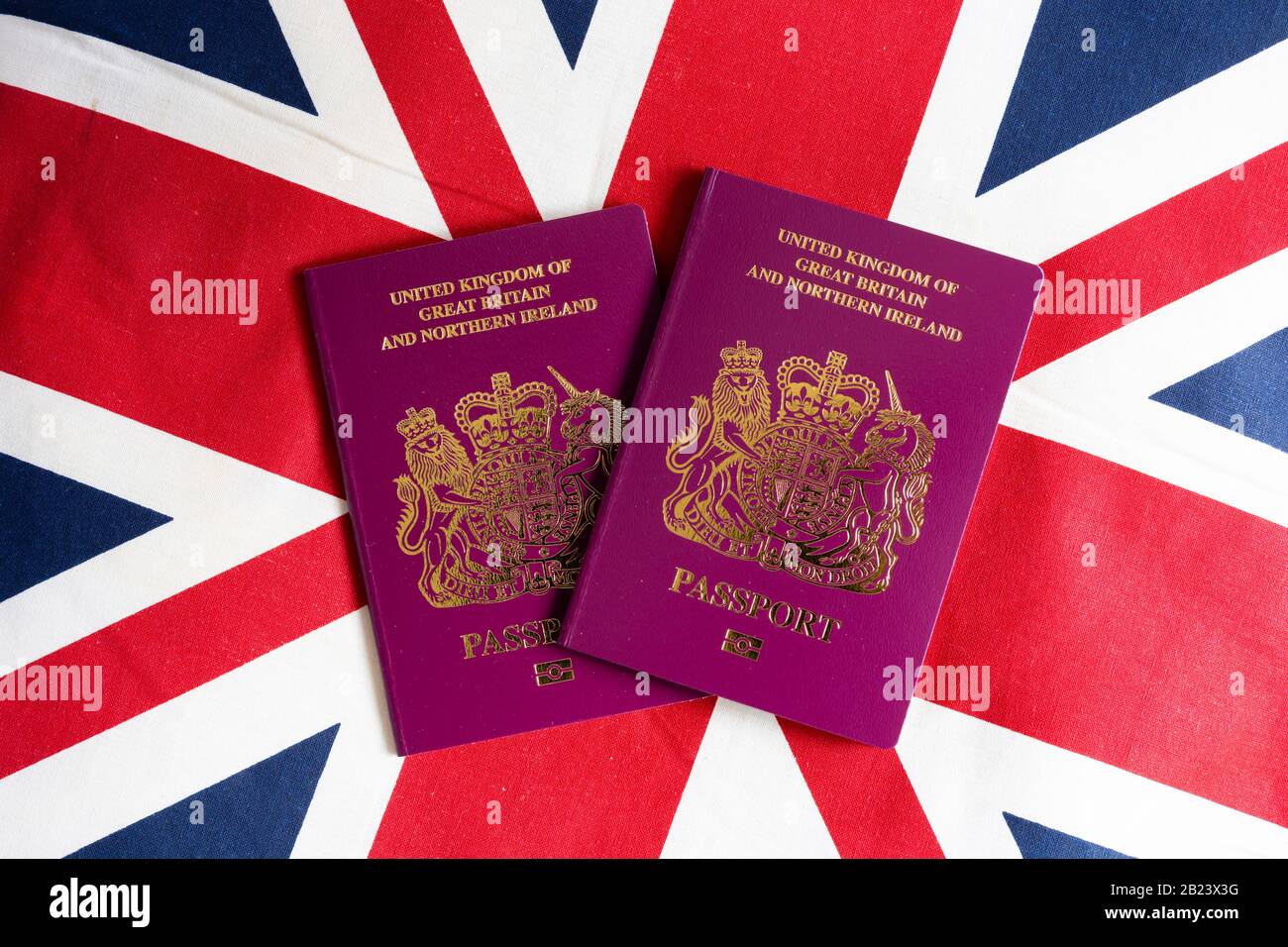 Pair of United Kingdom of Great Britain and Northern Ireland maroon passports on Union Jack background Stock Photo