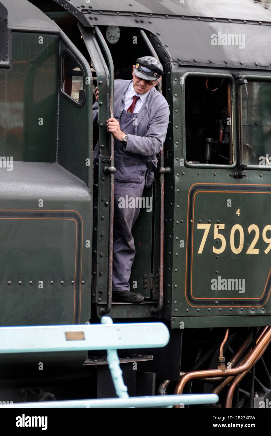 A steam engine driver on the footplate of the steam locomotive, No: 75029. It is ‘The Green Knight’ at Grosmont rail station, part of the NYMR (North Stock Photo