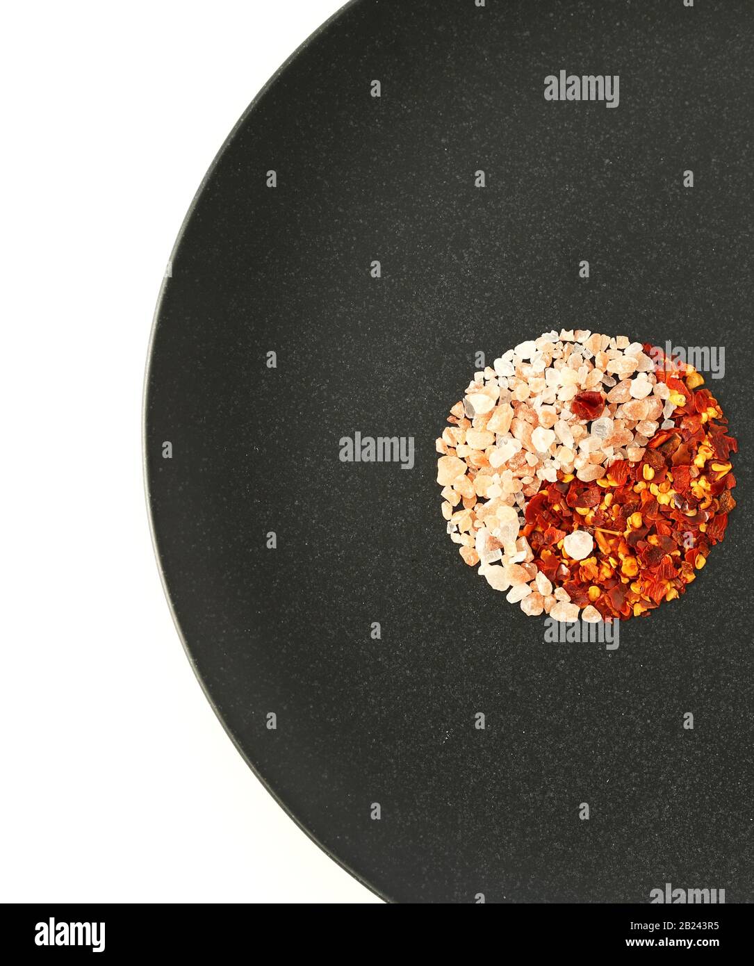 Yin Yang from food Himalayan salt and chili, flat lay, black plate