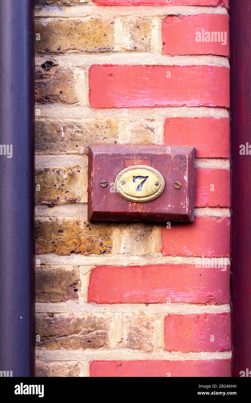 Wooden sign on a brick wall with the house number 7 Stock Photo