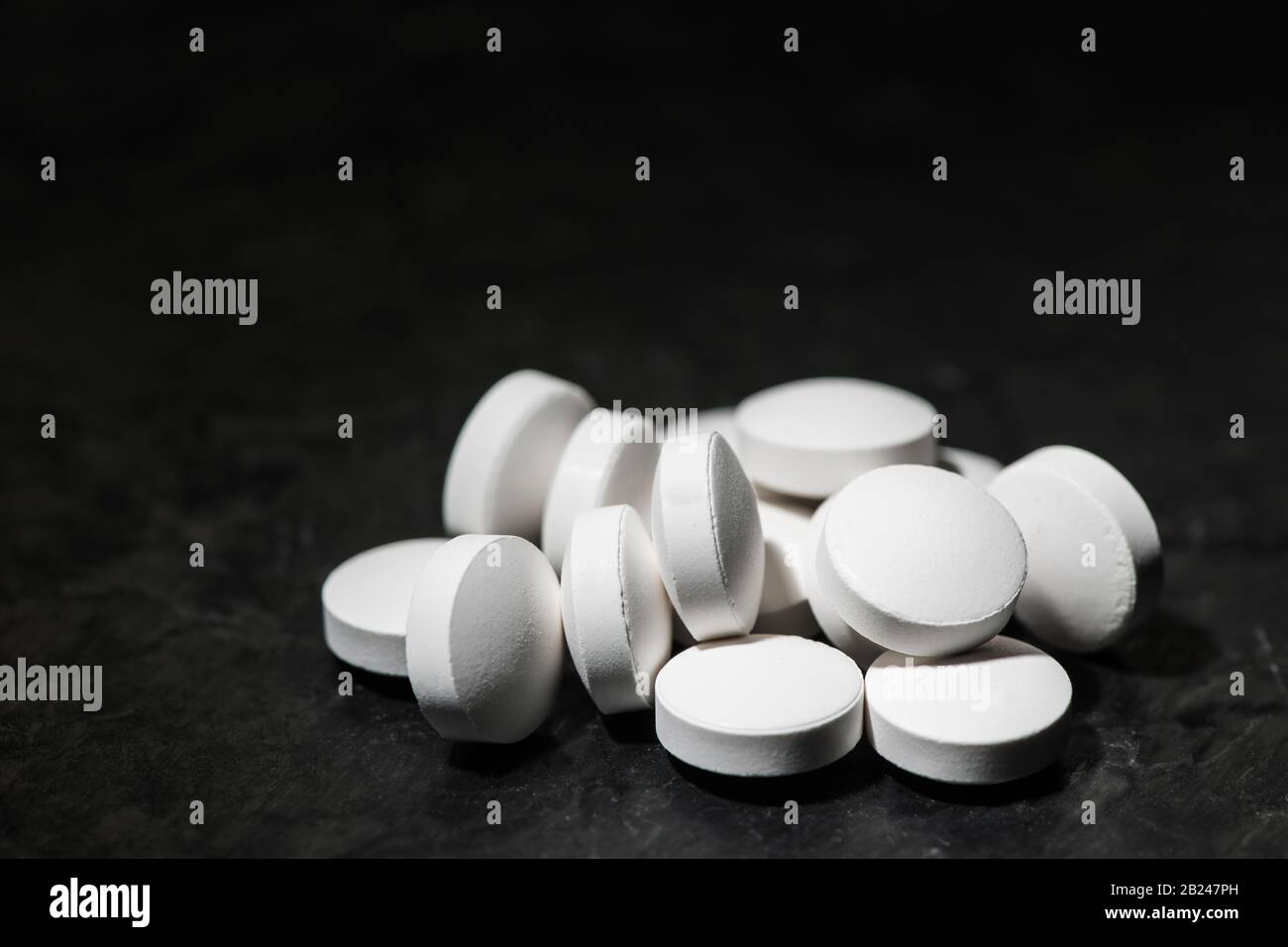 Close-up of piled round tablets on a slate monochrome with dark background. Stock Photo