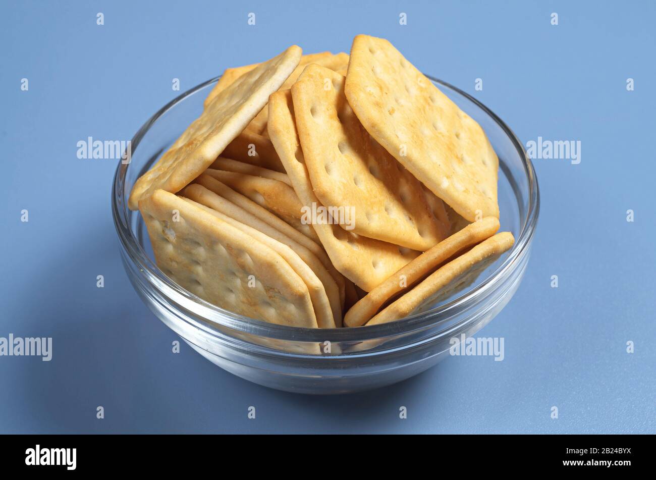 Square crackers in bowl on blue table Stock Photo