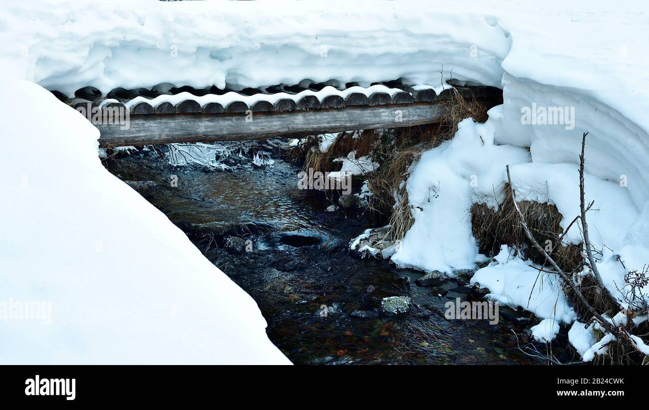 A bridge crossing a creek full of fresh snow Stock Photo - Alamy