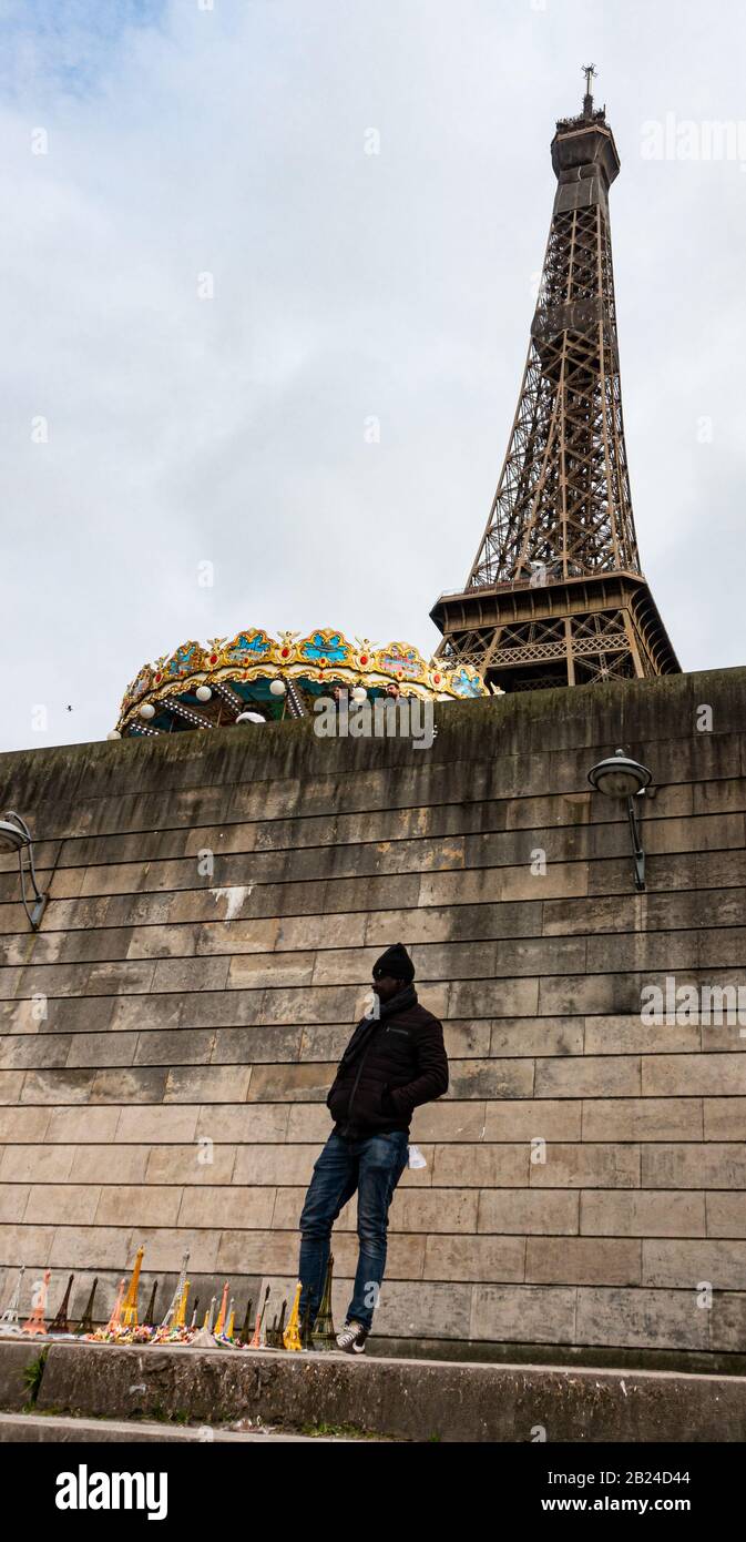 A street trader selling ornamental Eiffel Tower souvenirs beneath the Eiffel Tower, Paris, France Stock Photo