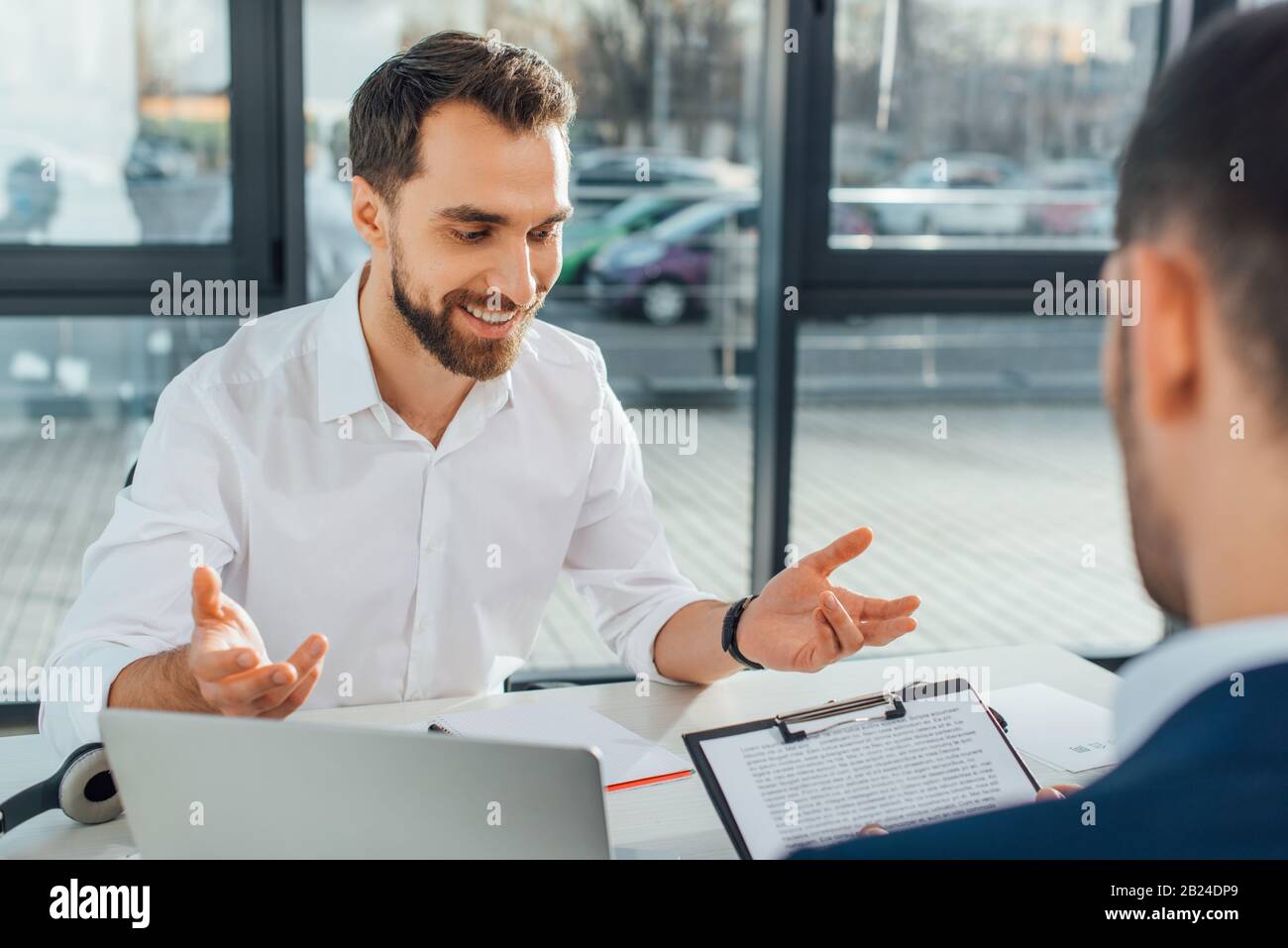 smiling translator working with businessman and documents in modern ...