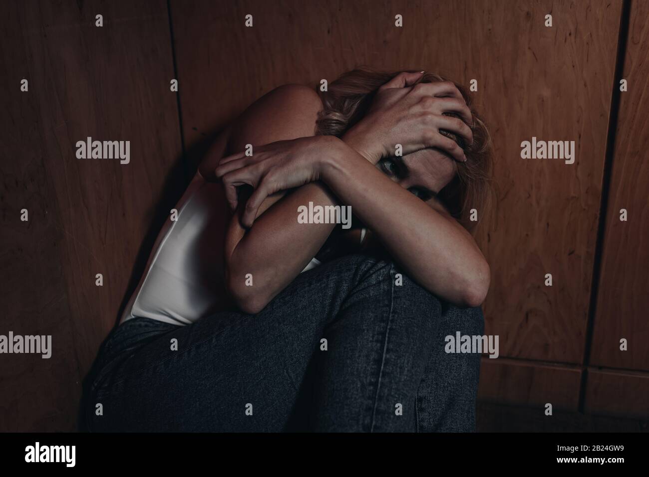 Scared woman hiding in corner Stock Photo - Alamy