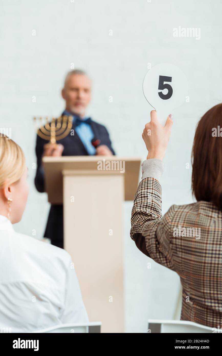 back view of buyer showing auction paddle with number five to