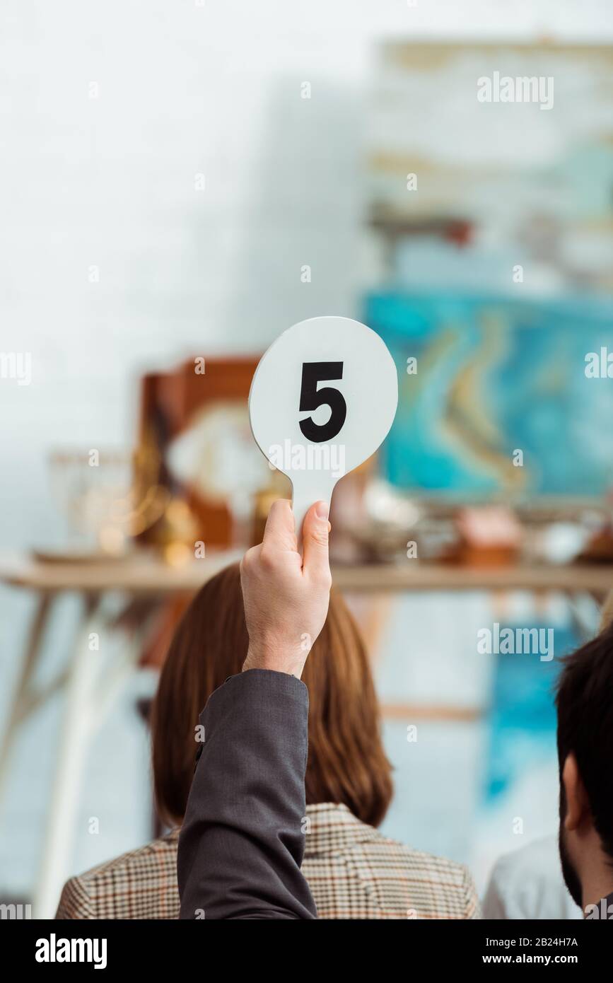 cropped view of buyer showing auction paddle with number five during auction Stock Photo