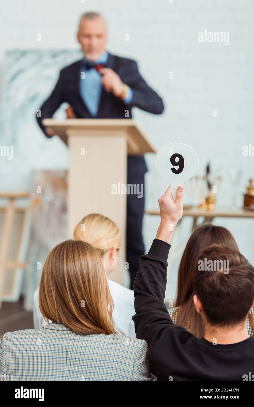 back view of buyer showing auction paddle with number nine during auction Stock Photo
