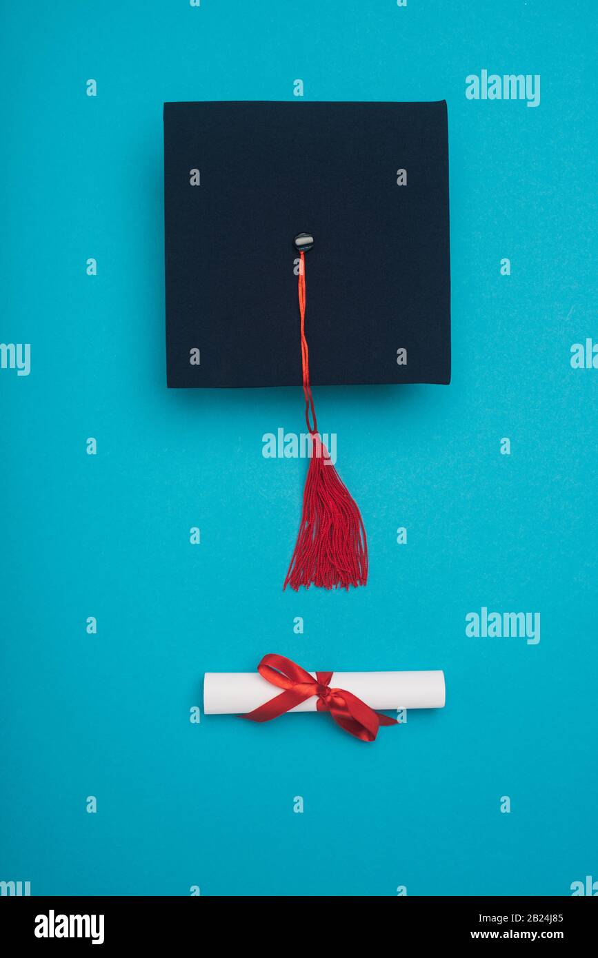 Top view of graduation cap with red tassel and diploma on blue ...